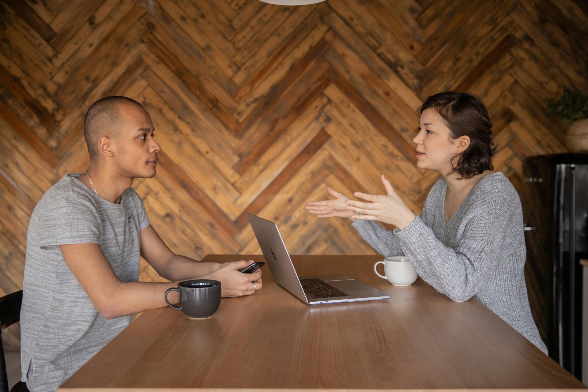 A man and a woman are sitting at a table with a laptop.