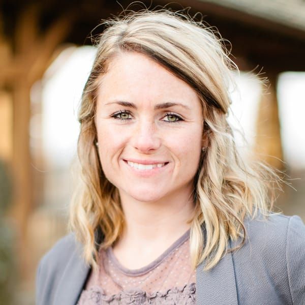 A woman with blonde hair and green eyes is smiling for the camera.