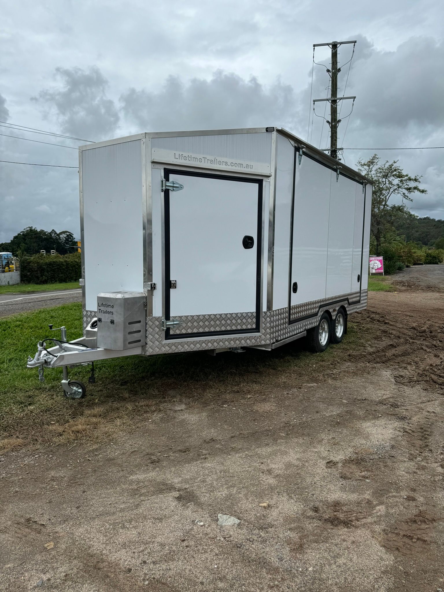 A Travel Trailer With Beach Scene Graphics Parked Outdoors — Rod's Engineering & Lifetime Trailers in Bli Bli, QLD