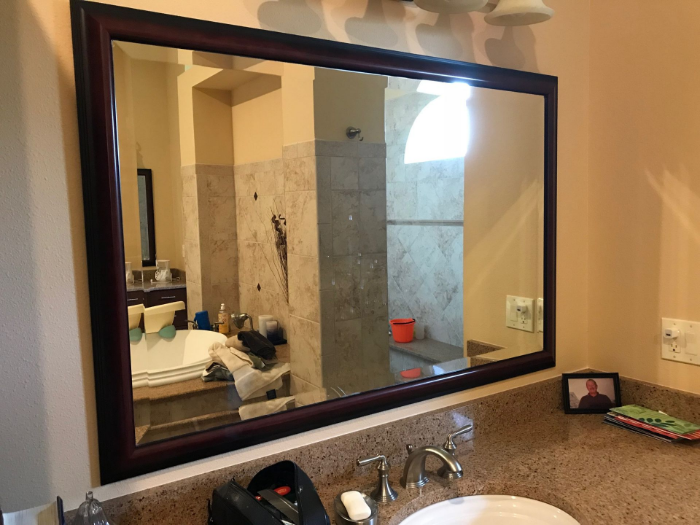 Bathroom with a large rectangular mirror reflecting a sink, bathtub, and tiled shower area.