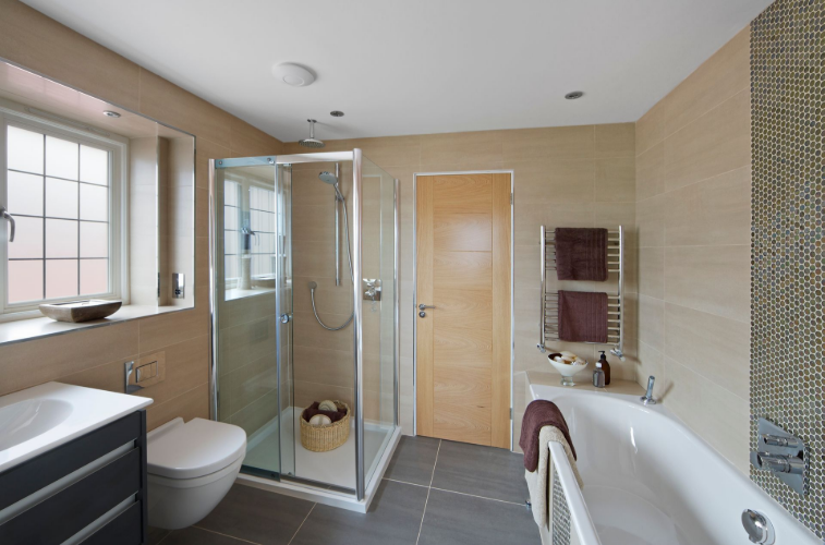 A luxurious bathroom with cream tiles on the walls and a shower area with glass shower doors.