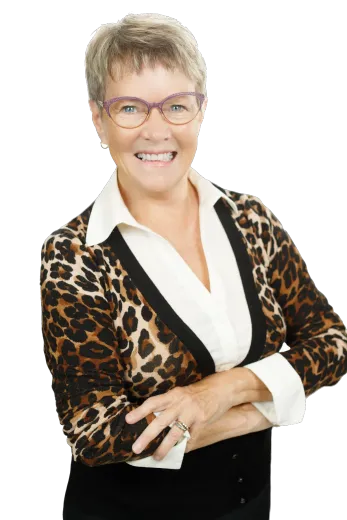 Woman with glasses and a leopard print sweater smiles with arms crossed.