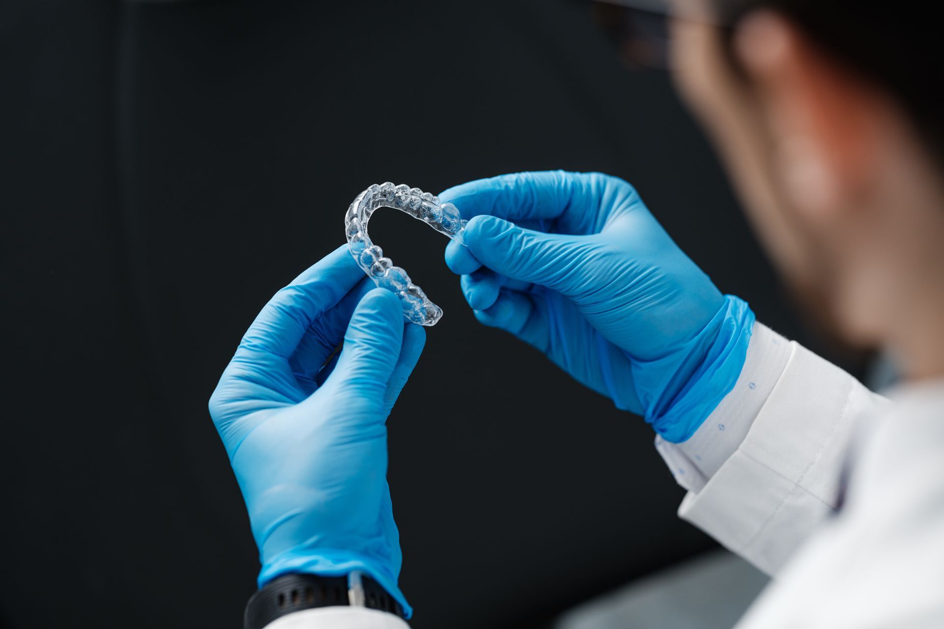 Hands of dentist holding dental aligner.