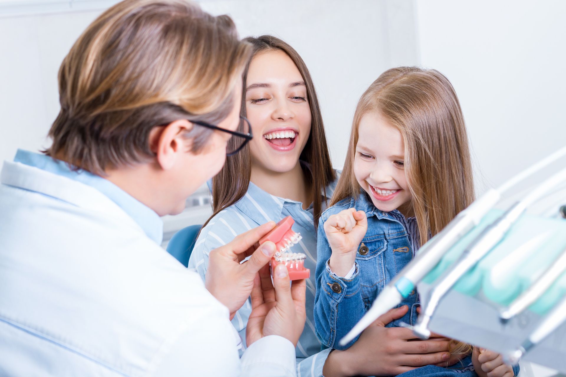 A woman and a little girl are sitting at a dentist 's office.