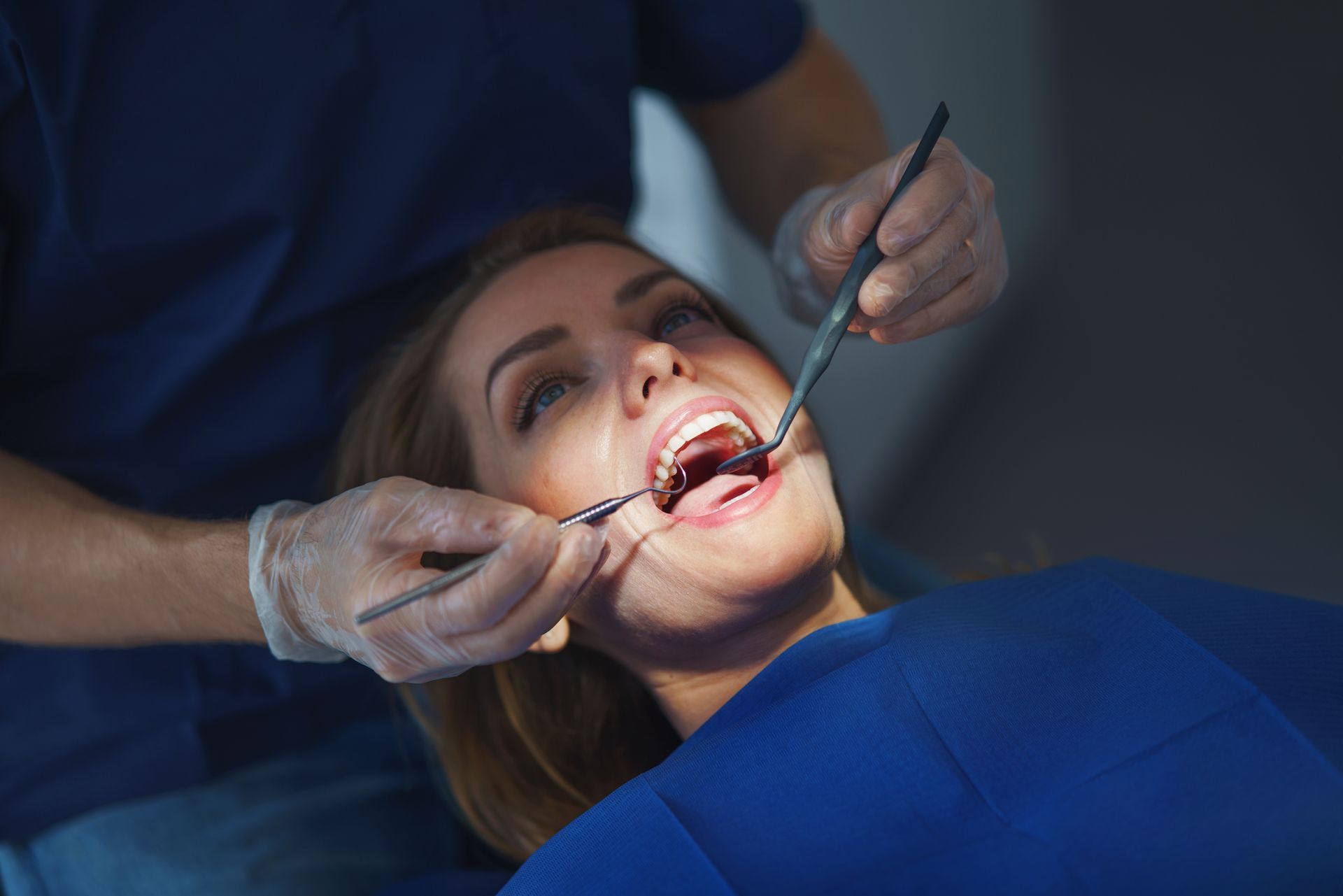 A woman is having her teeth examined by a dentist.