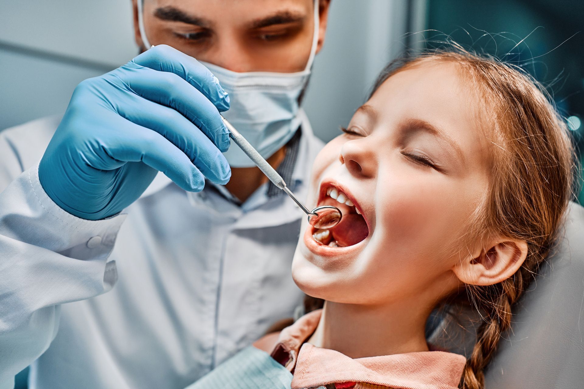 Child orthodontist gently examining a young patient’s teeth during a dentist appointment.