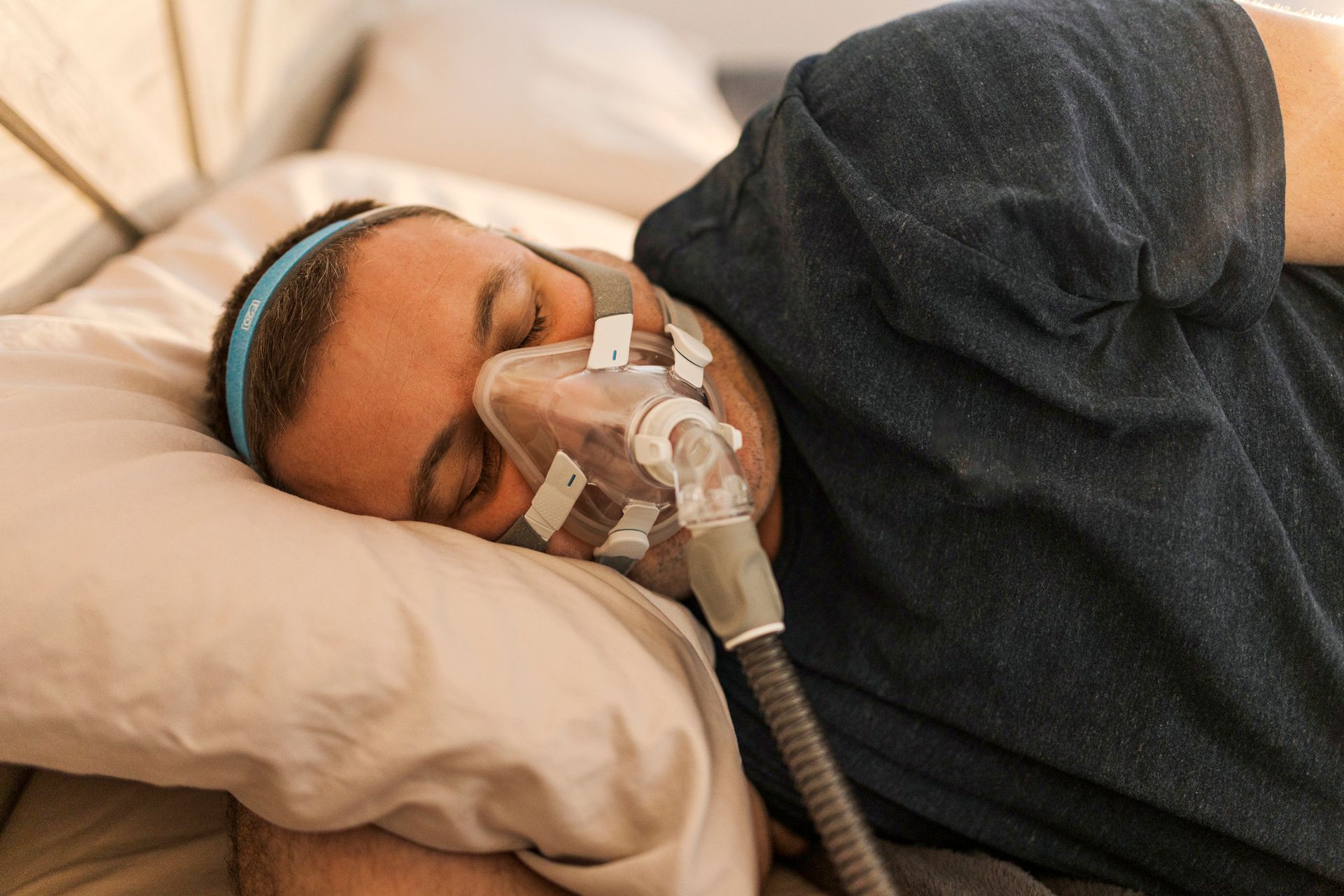 A man is sleeping in bed with an oxygen mask on his face. A man is sleeping in bed with an oxygen mask on his face.