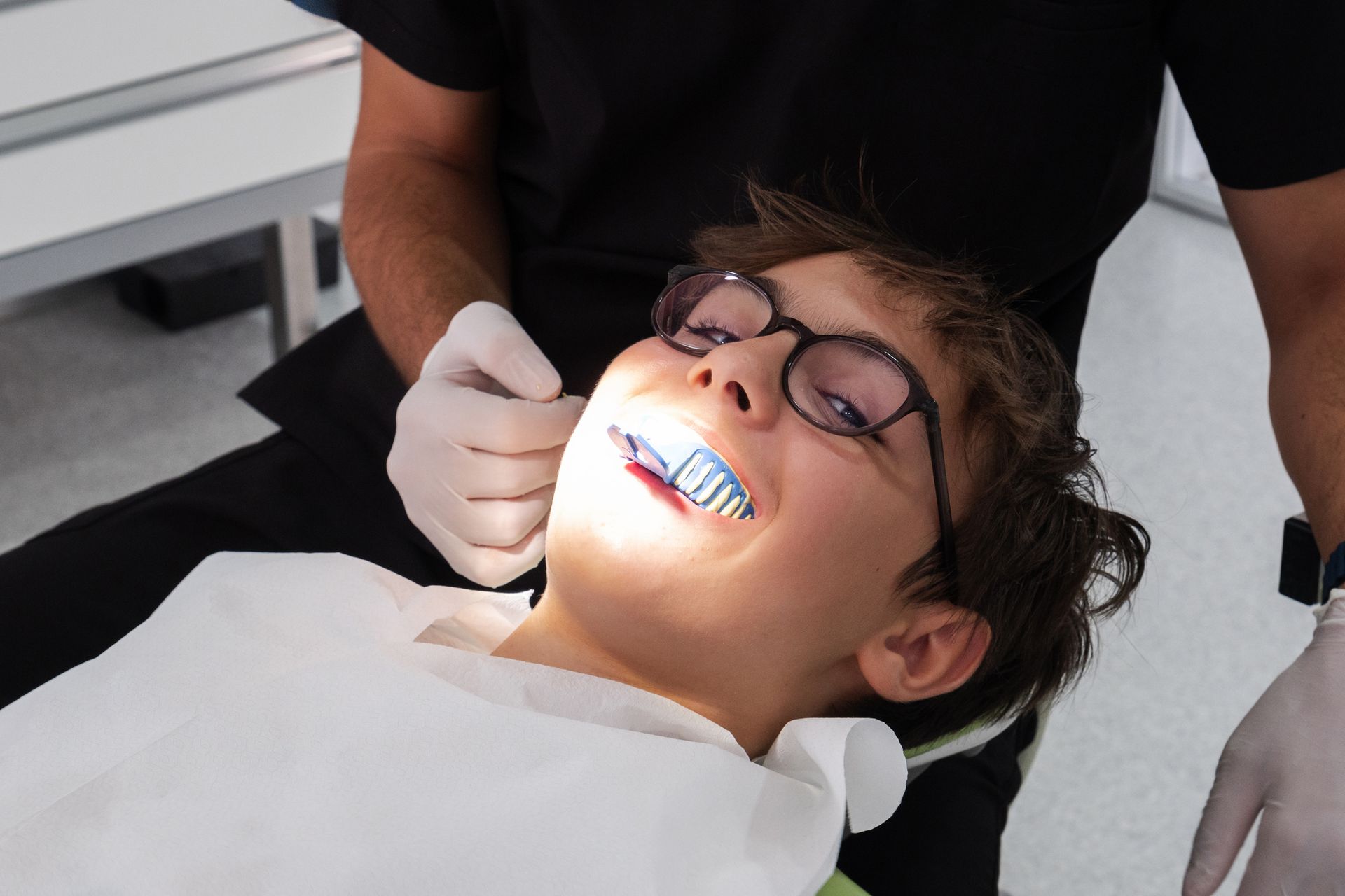 Child orthodontist removing braces from young patient at end of orthodontic treatment.