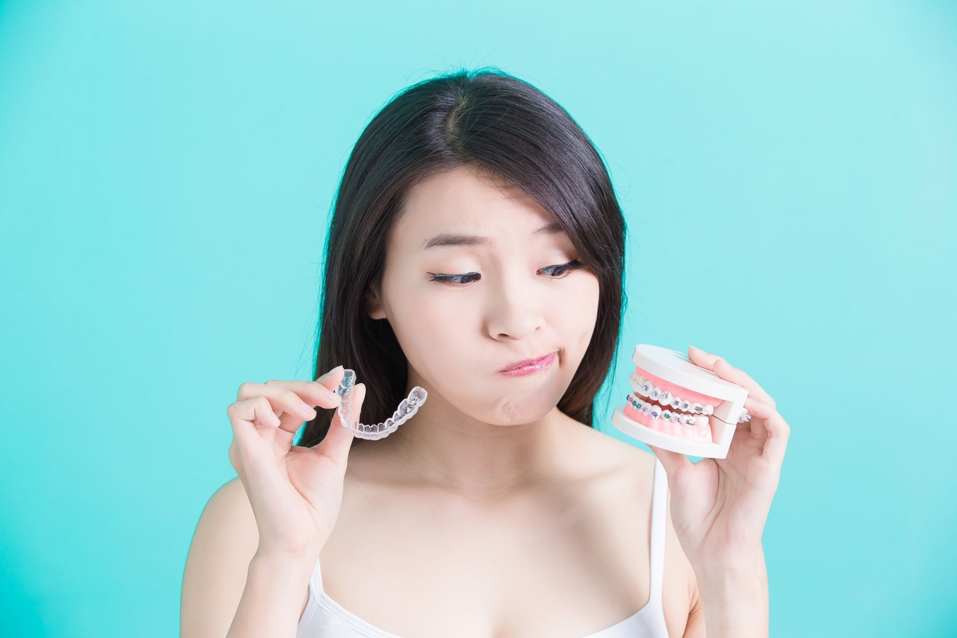 A woman choosing between a clear dental aligner or braces.