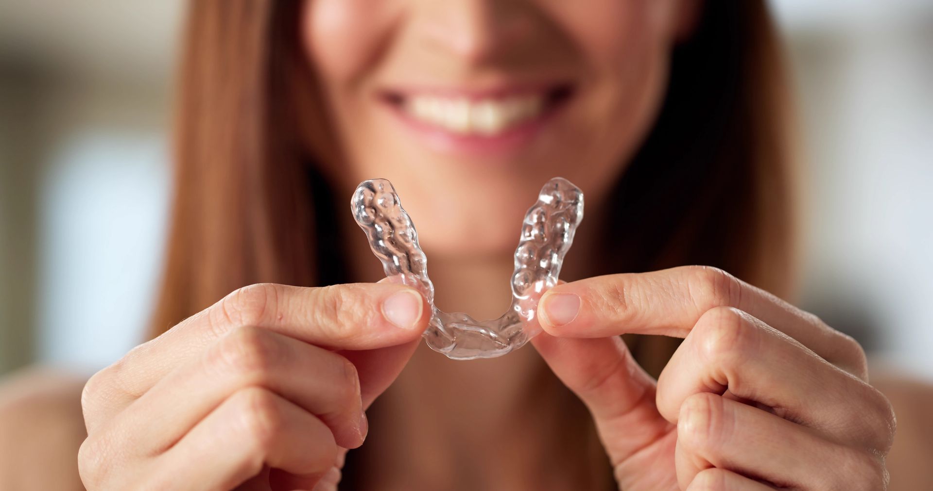 Close-up picture of a woman fitting a clear dental aligner.
