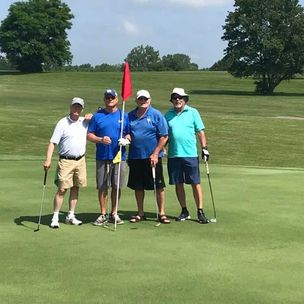A group of men are posing for a picture on a golf course.