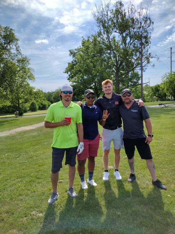 A group of men are posing for a picture on a golf course.