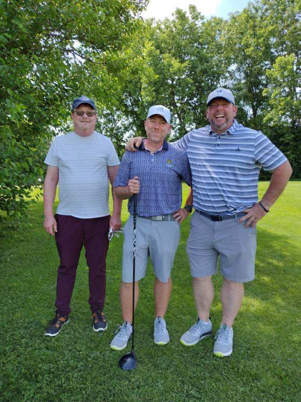 Three men are posing for a picture on a golf course.