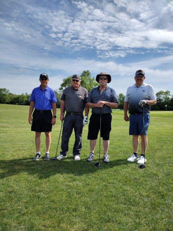 A group of men are standing on a golf course holding golf clubs.