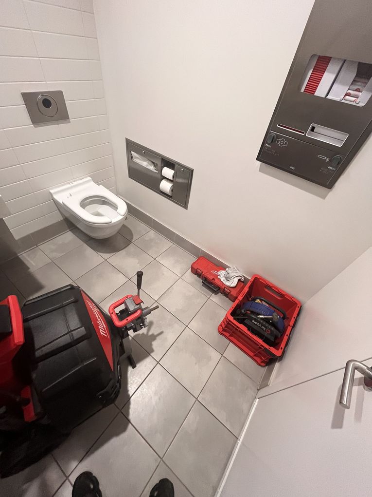 A bathroom with a toilet and a vacuum cleaner