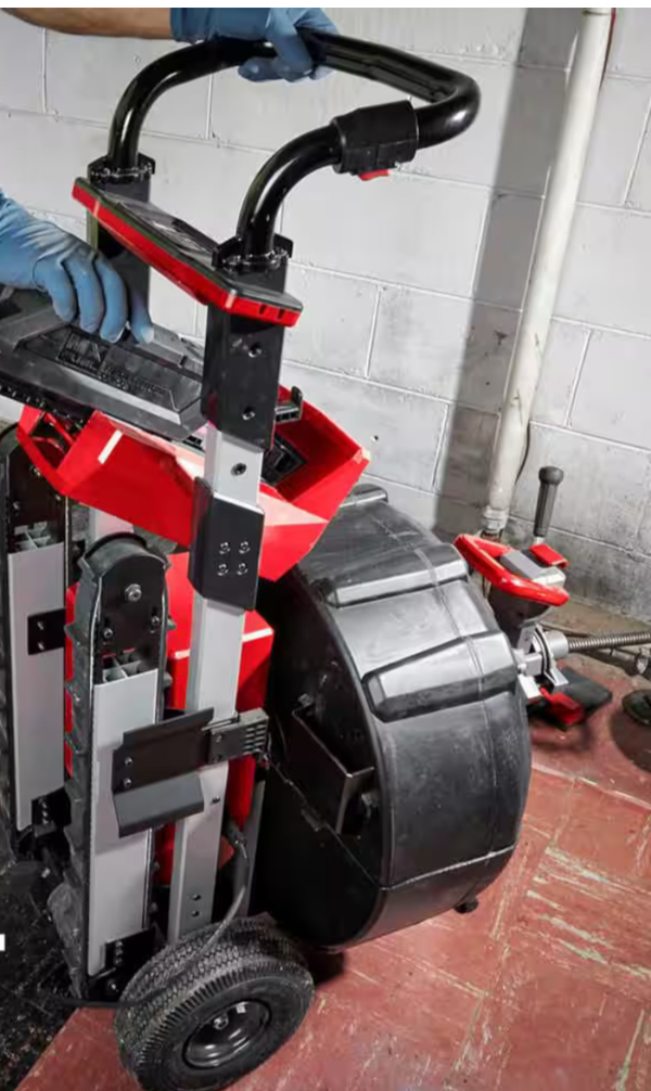 A person is holding the handle of a red and black machine.