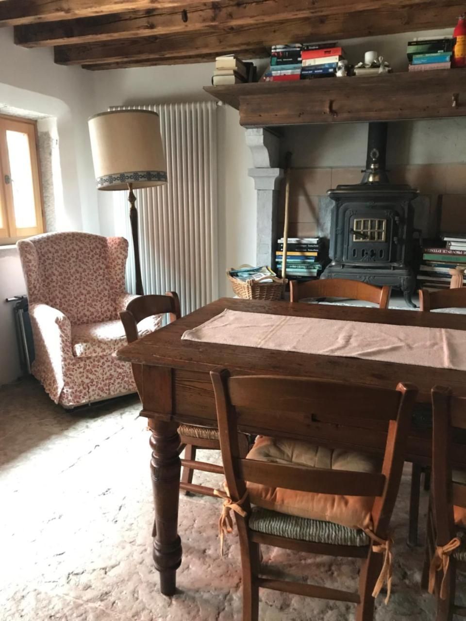 Accogliente sala da pranzo con tavolo in legno, sedie e poltrona vicino al camino.