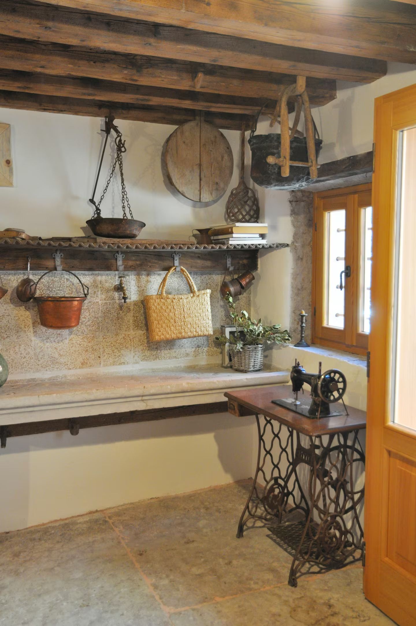 Angolo cucina rustico con ripiani in legno e una macchina da cucire d'epoca.