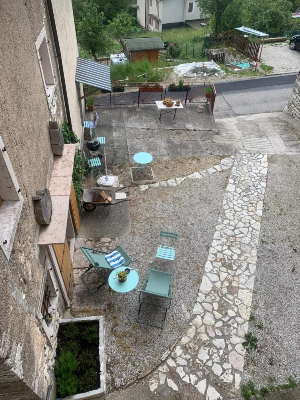 Patio con sedie e tavoli color verde acqua, sentiero in pietra, vicino a un edificio.