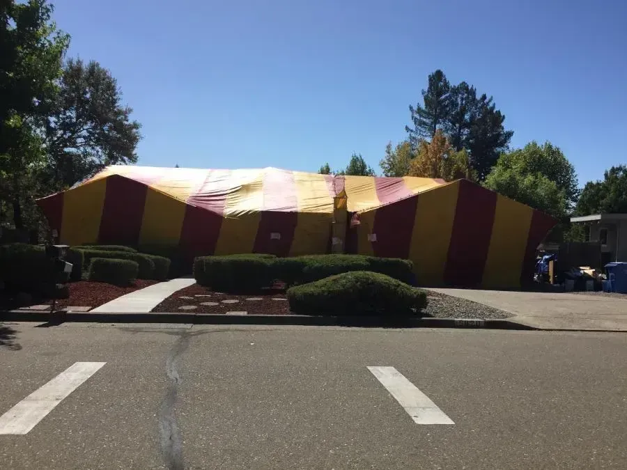 A red and yellow tent is in front of a house