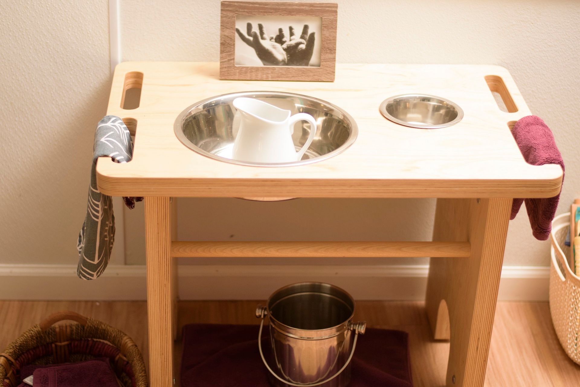 A wooden table with two stainless steel sinks and a picture of hands on it.