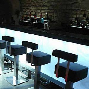 Un bar avec une rangée de tabourets de bar devant lui