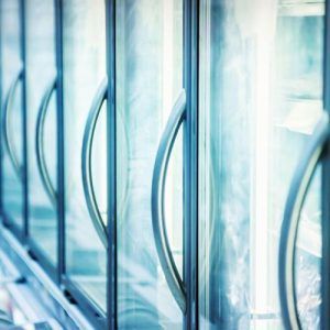 Une rangée de réfrigérateurs avec portes et poignées en verre dans un magasin.