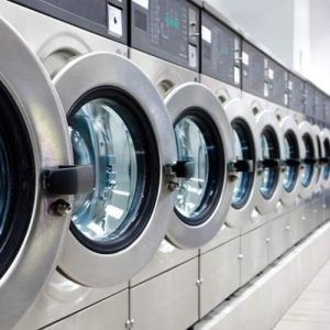 Une rangée de machines à laver est alignée dans une laverie automatique.