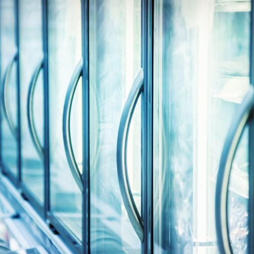 Une rangée de portes vitrées avec poignées dans un réfrigérateur.