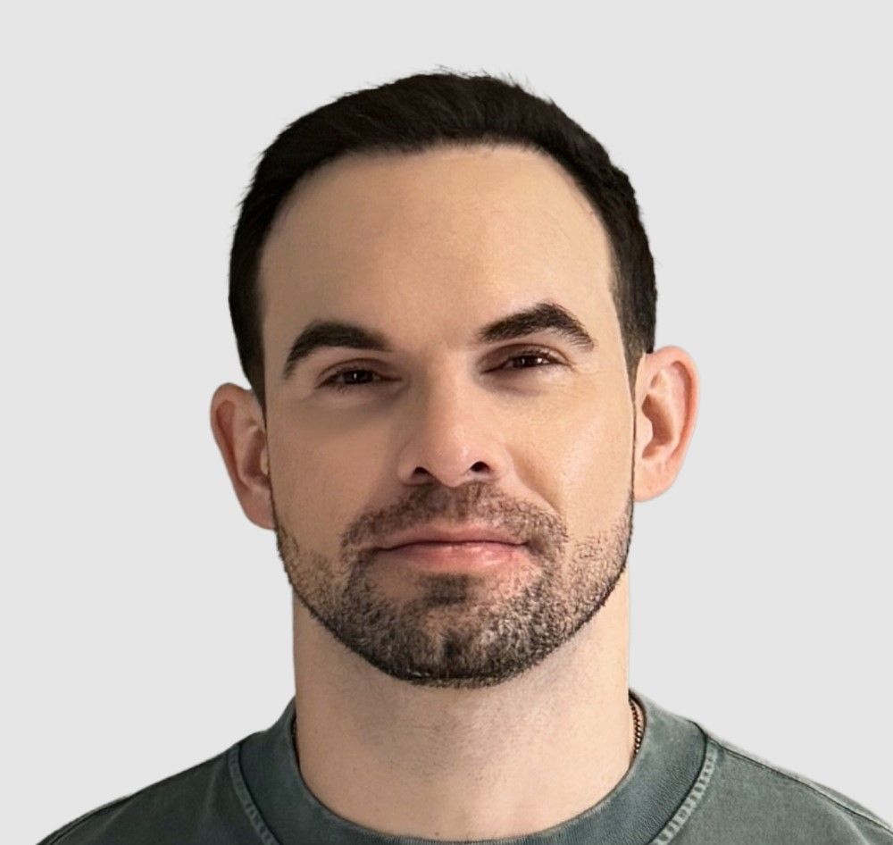 Man with dark hair and stubble, looking directly at the camera.