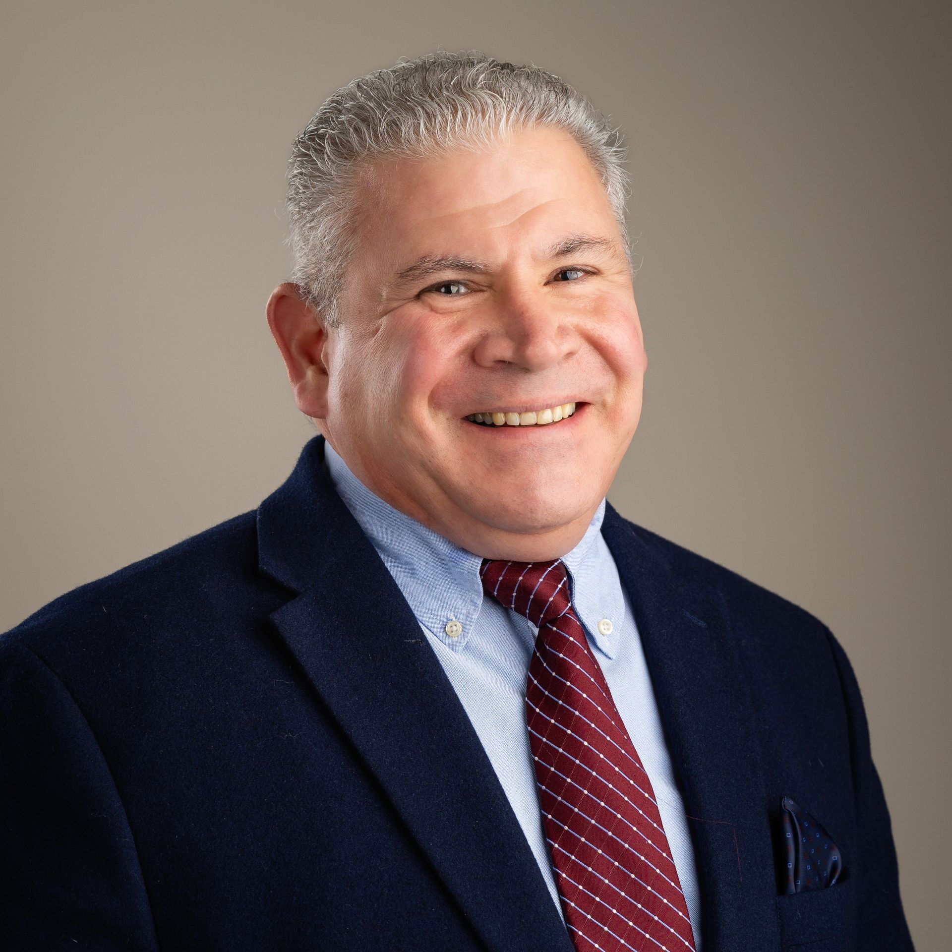 Man wearing a suit and tie smiling at the camera.