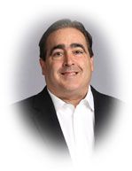 Man in a black suit jacket and white shirt, smiling.