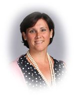 Woman with dark hair, wearing pearls and a polka-dot top, smiling.