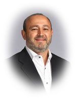 Man with beard, in suit jacket, smiling at the camera.