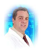 Man in white coat, smiling, in front of a blue screen.