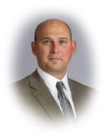 Man in suit and tie, looking at the camera, with a neutral expression.
