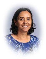 Woman with dark hair smiles, wearing a blue patterned top, against a soft blue background.