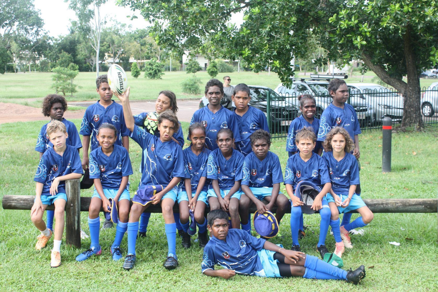 A group of children in blue shirts are posing for a picture