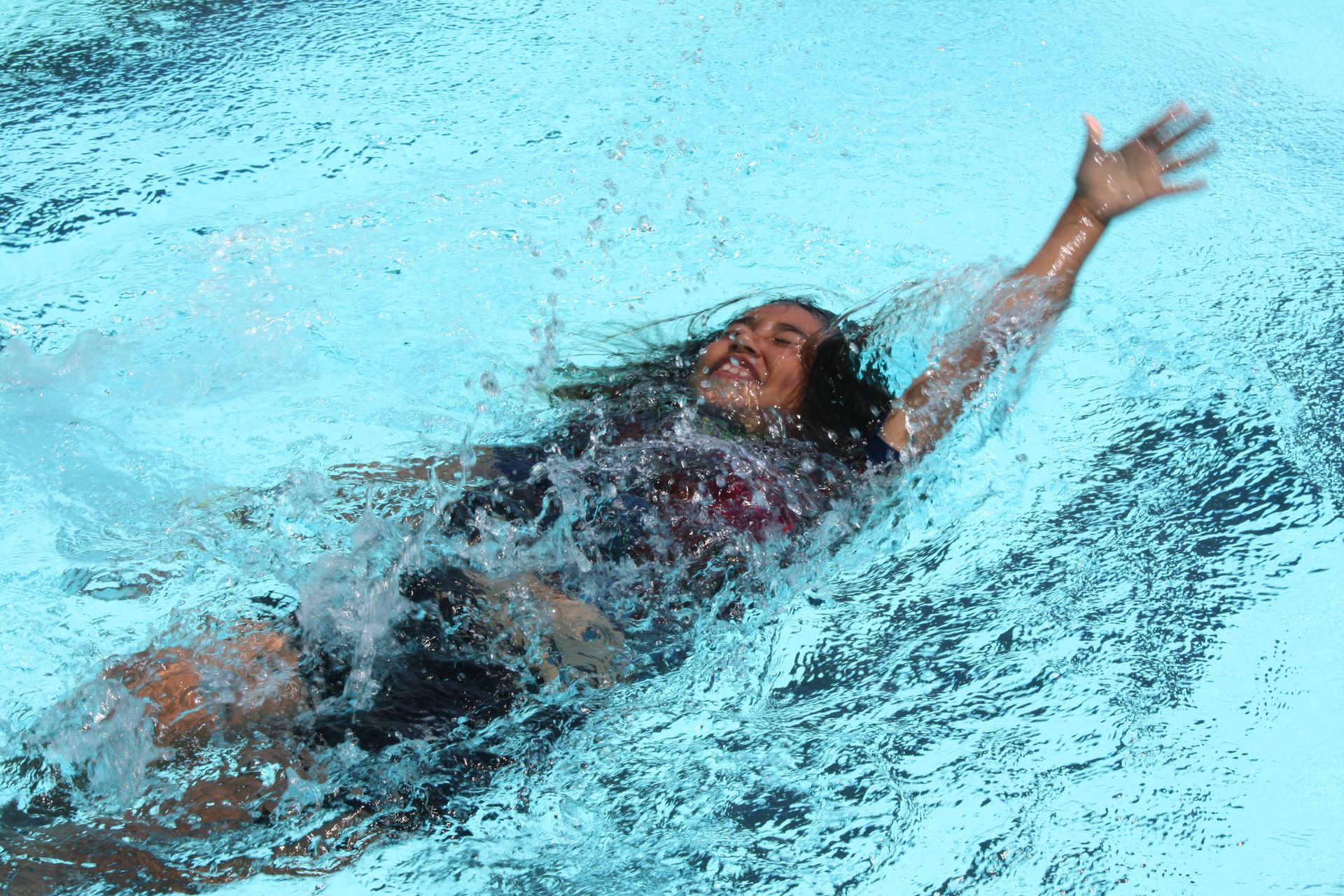 A woman is swimming in a pool with her arm outstretched.