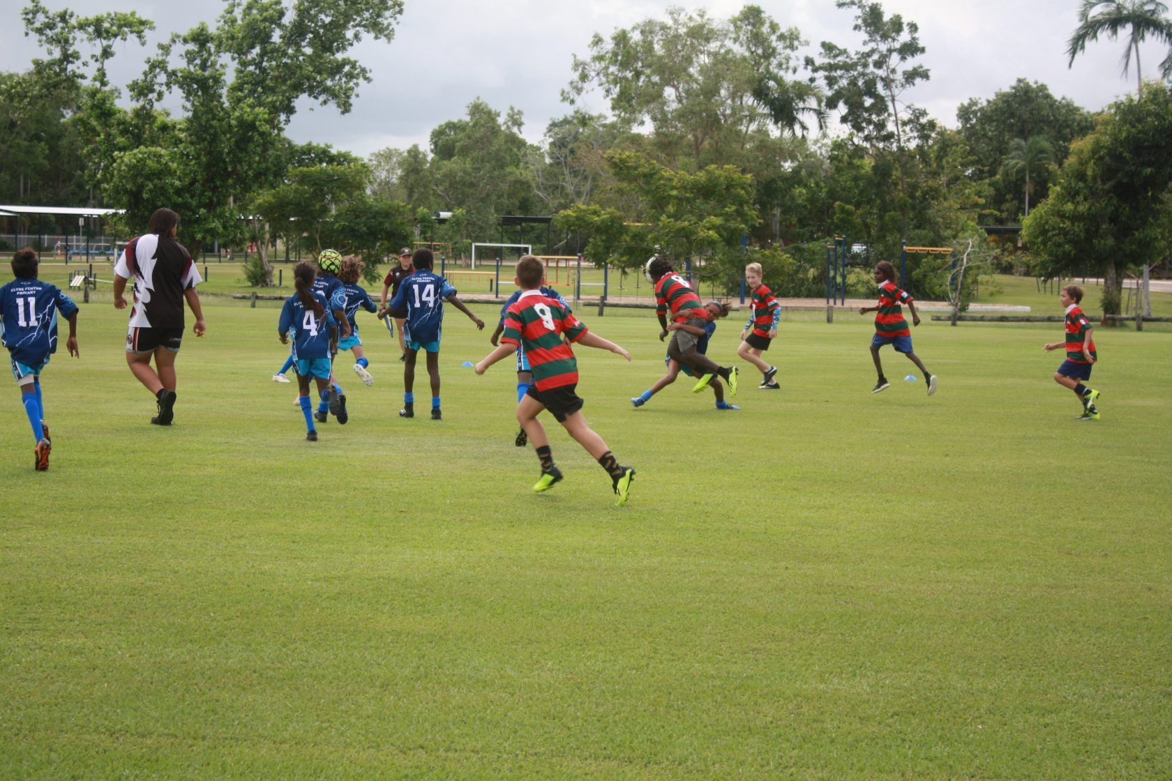 A group of children are playing a game of soccer on a lush green field.