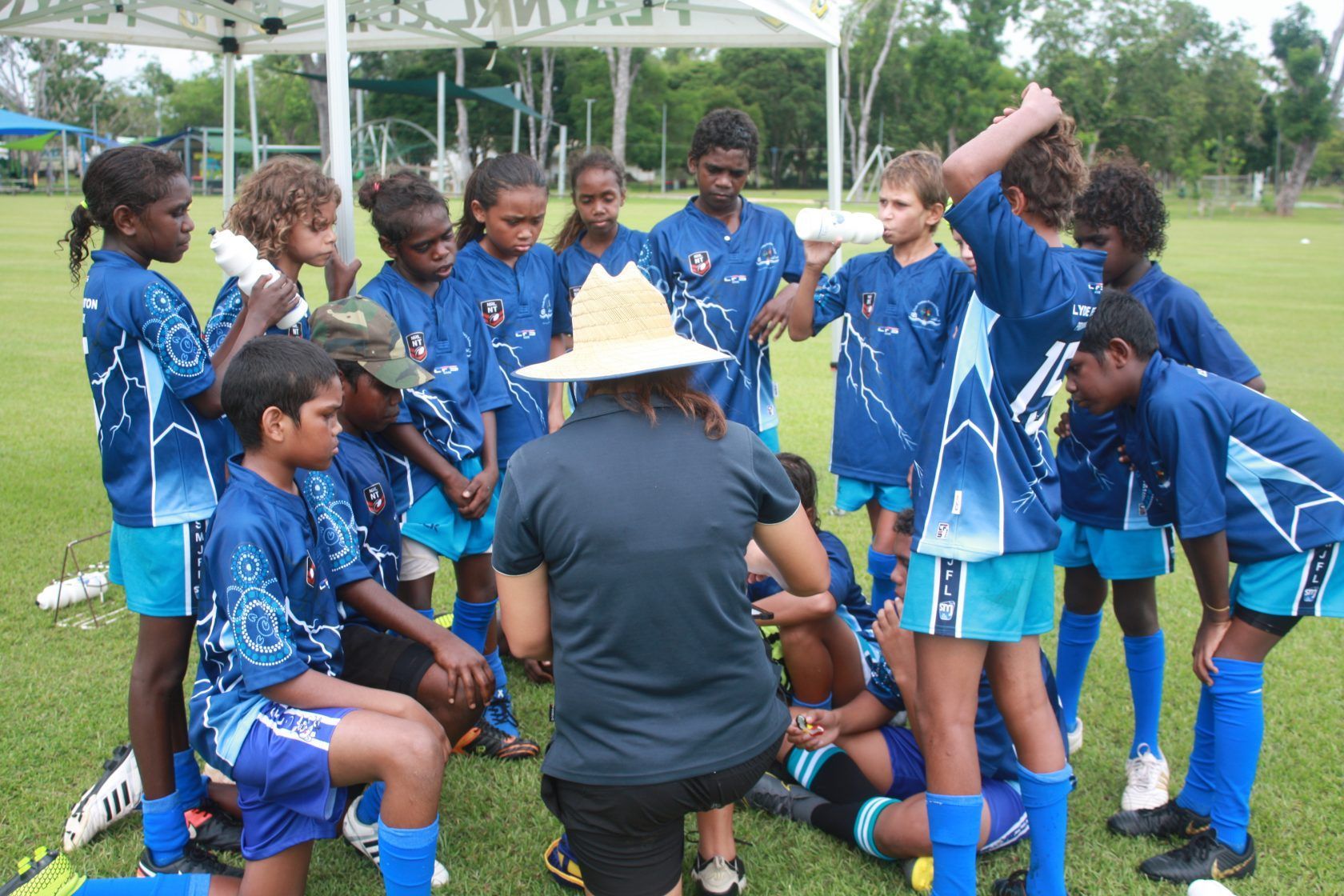 A man in a hat is talking to a group of children