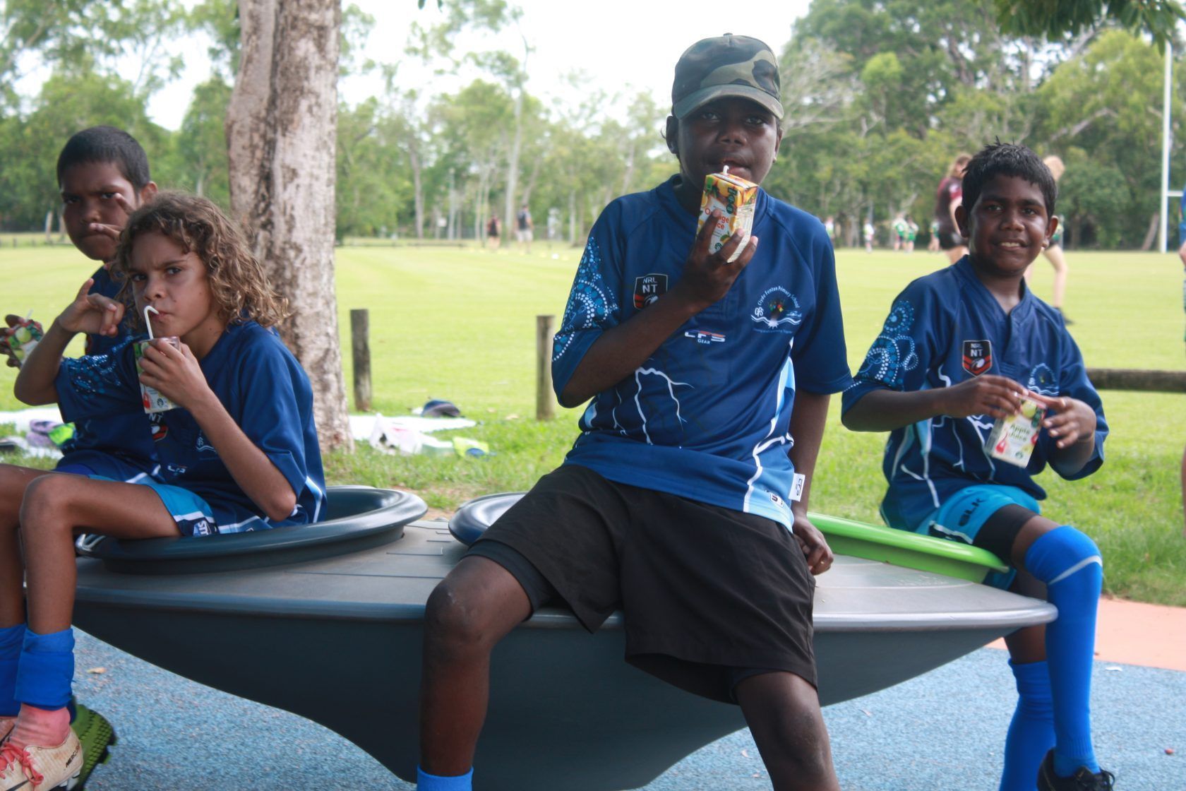 A group of children are sitting on a bench eating food