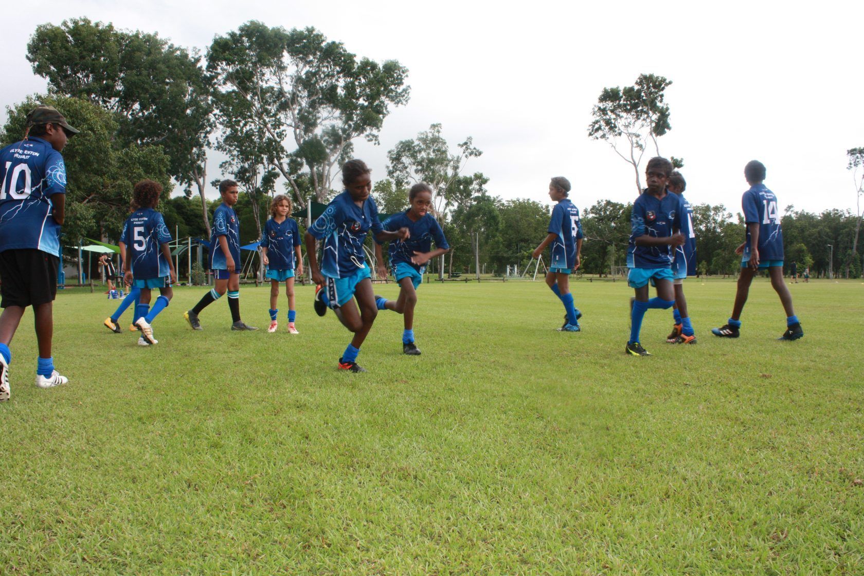 A group of children are playing soccer on a field and one of them has the number 10 on his shirt