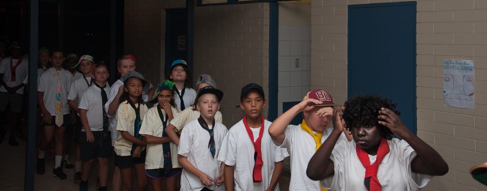 A group of children are standing in a hallway.