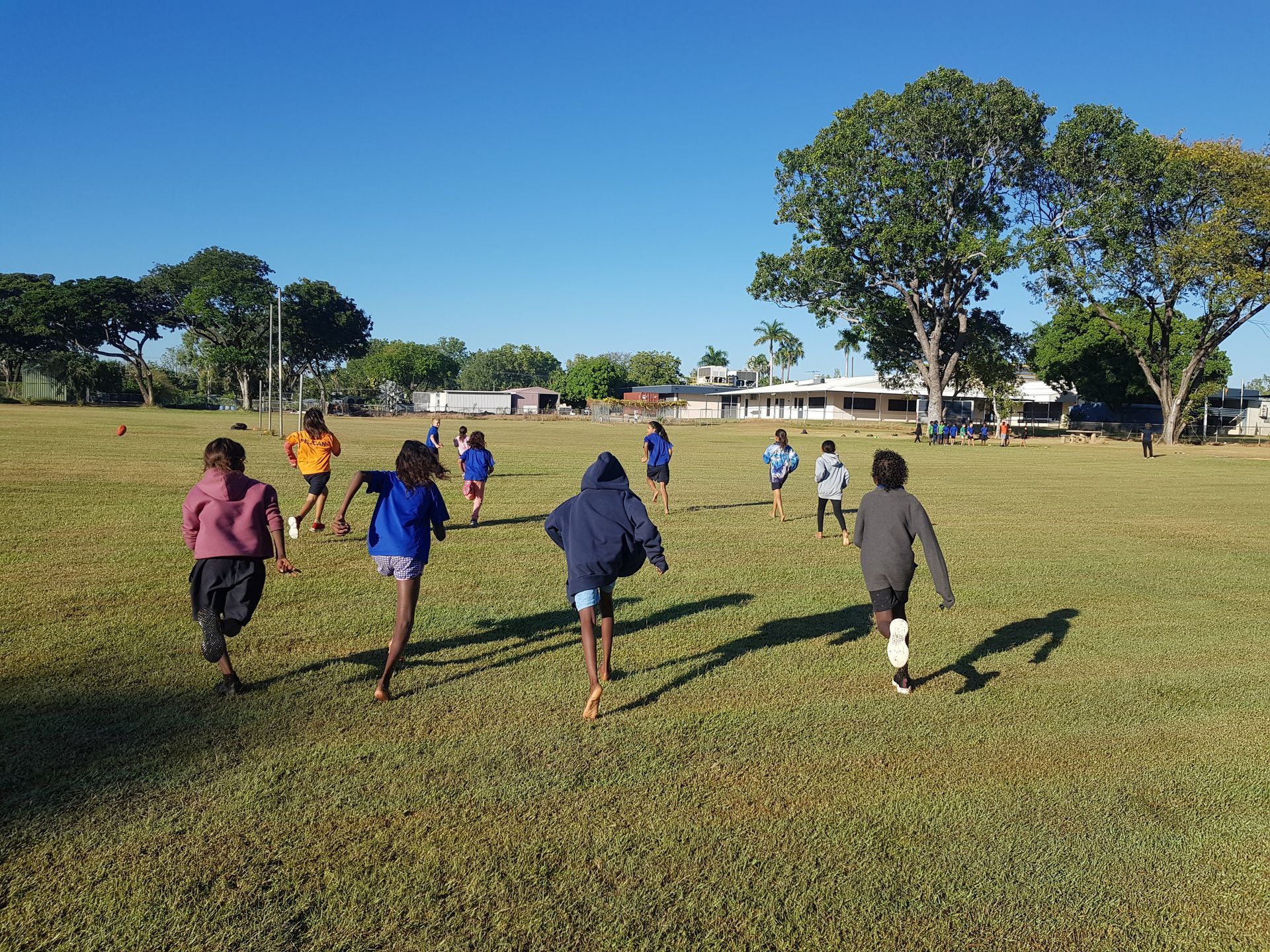 A group of children are running in a grassy field