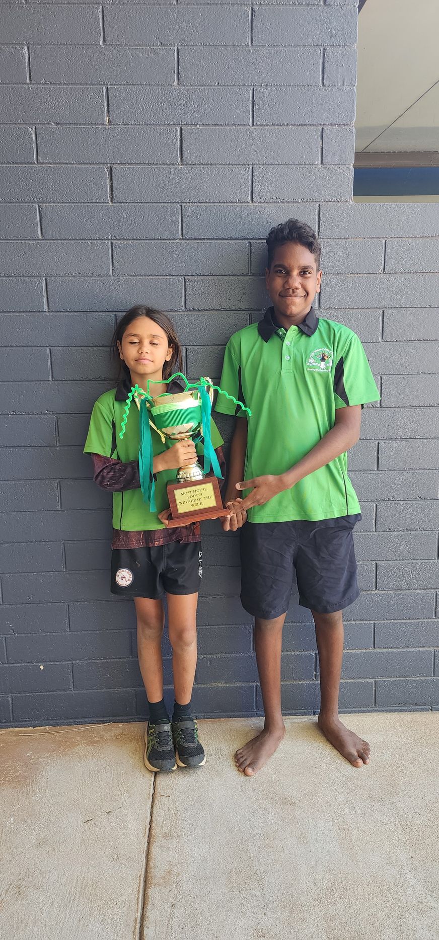 A boy and a girl are standing next to each other holding a trophy.