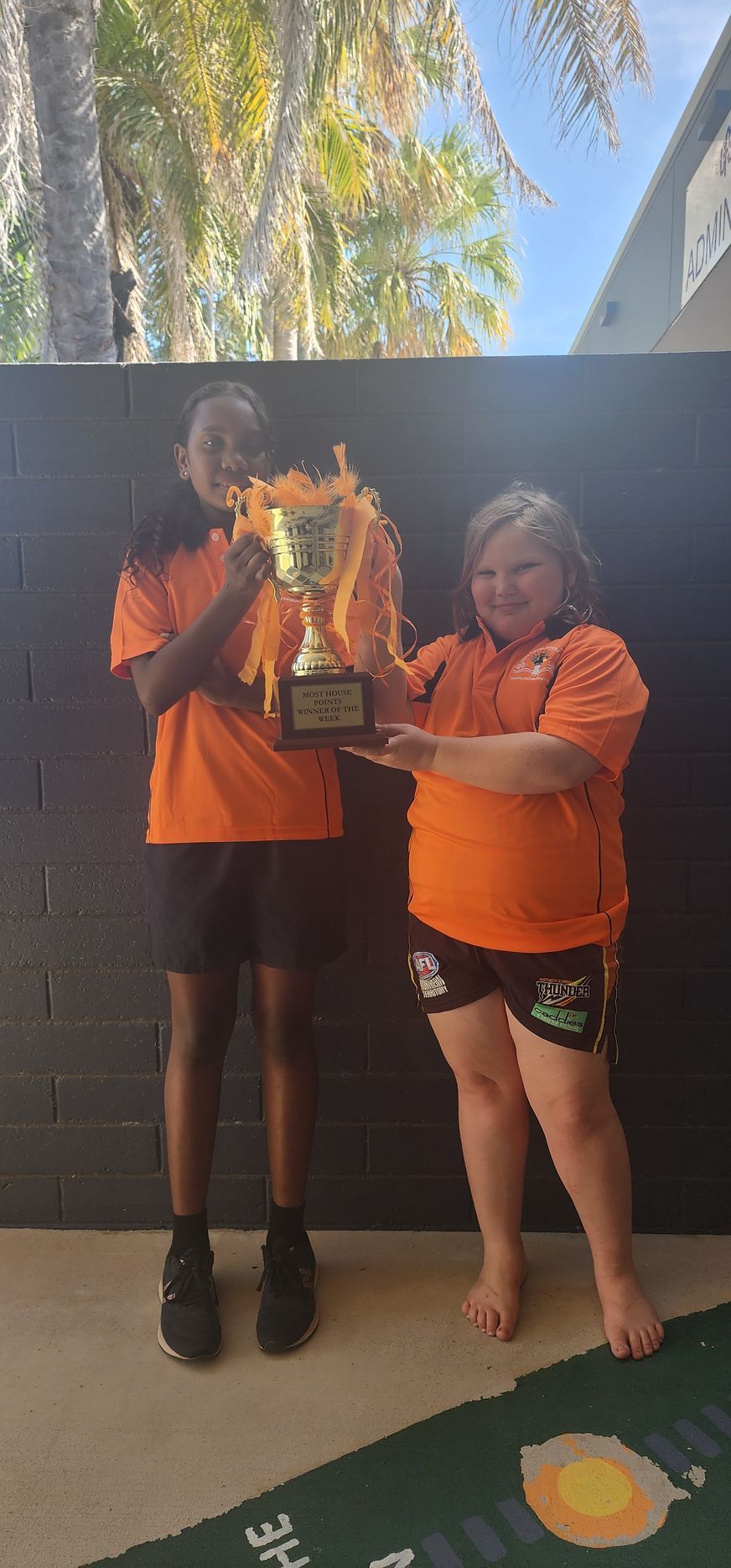 A boy and a girl are standing next to each other holding a trophy.