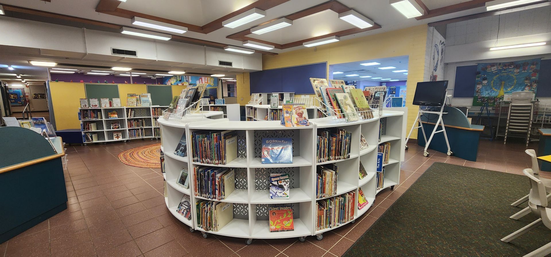 A library with a large round bookshelf filled with books.