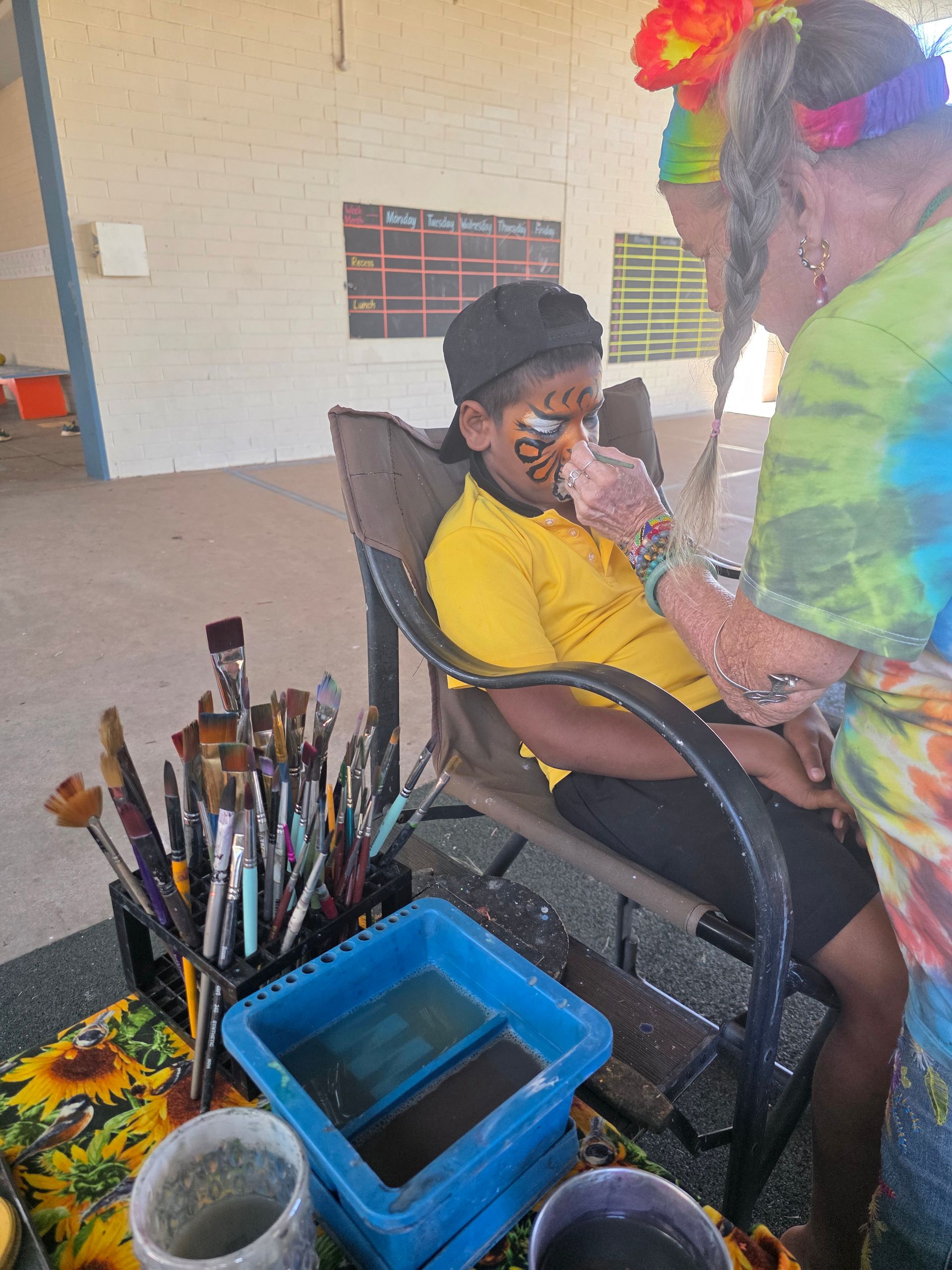 A child is sitting in a chair getting his face painted.
