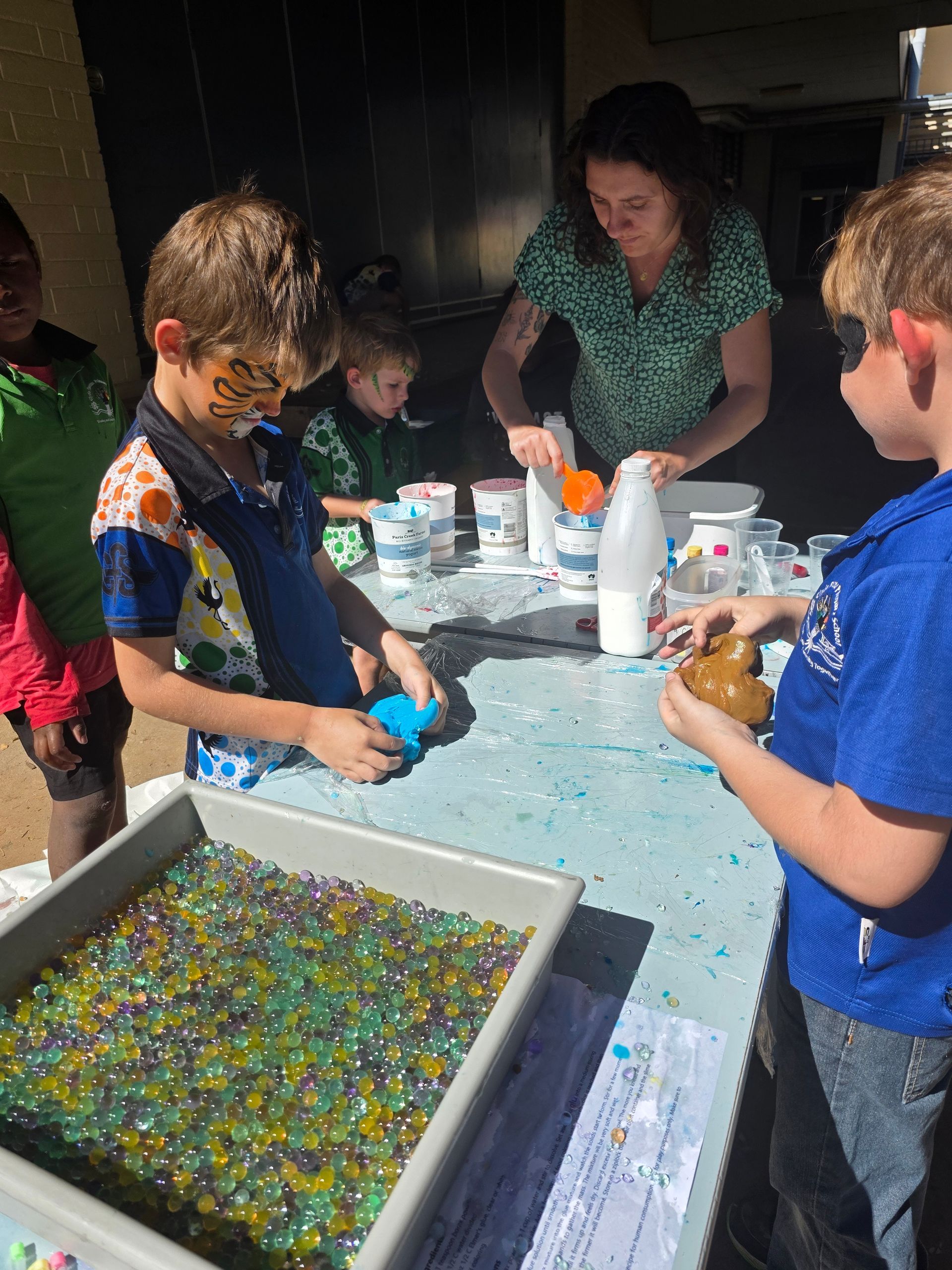 A group of children are playing with marbles on a table.